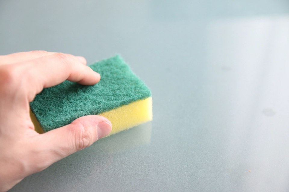 Hand reinigt eine Glasfläche mit einem Schwamm