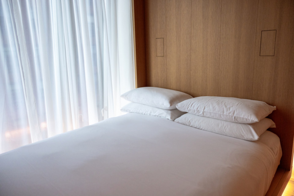 Frisch bezogenes Bett mit weißer Bettwäsche in einem hellen Schlafzimmer