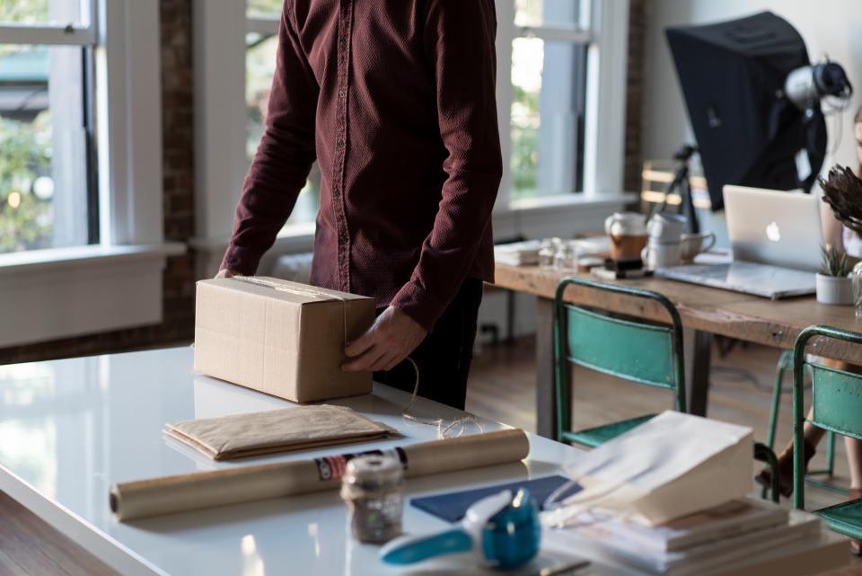 Person verpackt einen Umzugskarton an einem Tisch